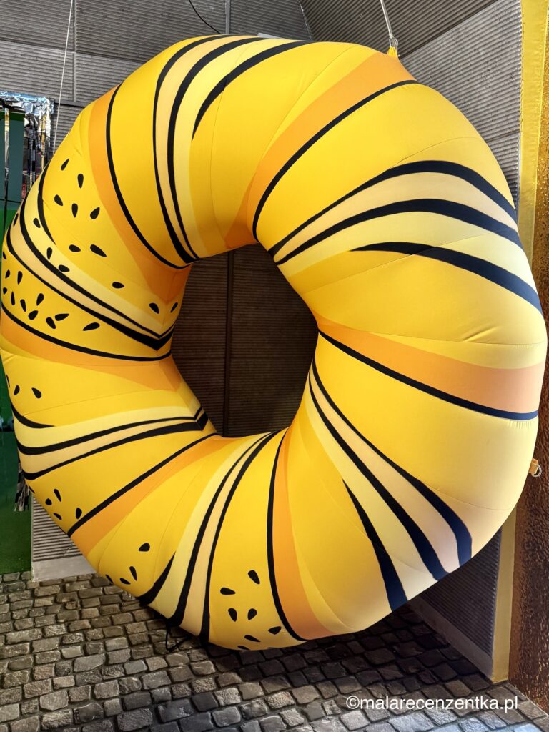 Duży, żółty balon w kształcie obwarzanka krakowskiego, wystawa w Muzeum balonów w Krakowie